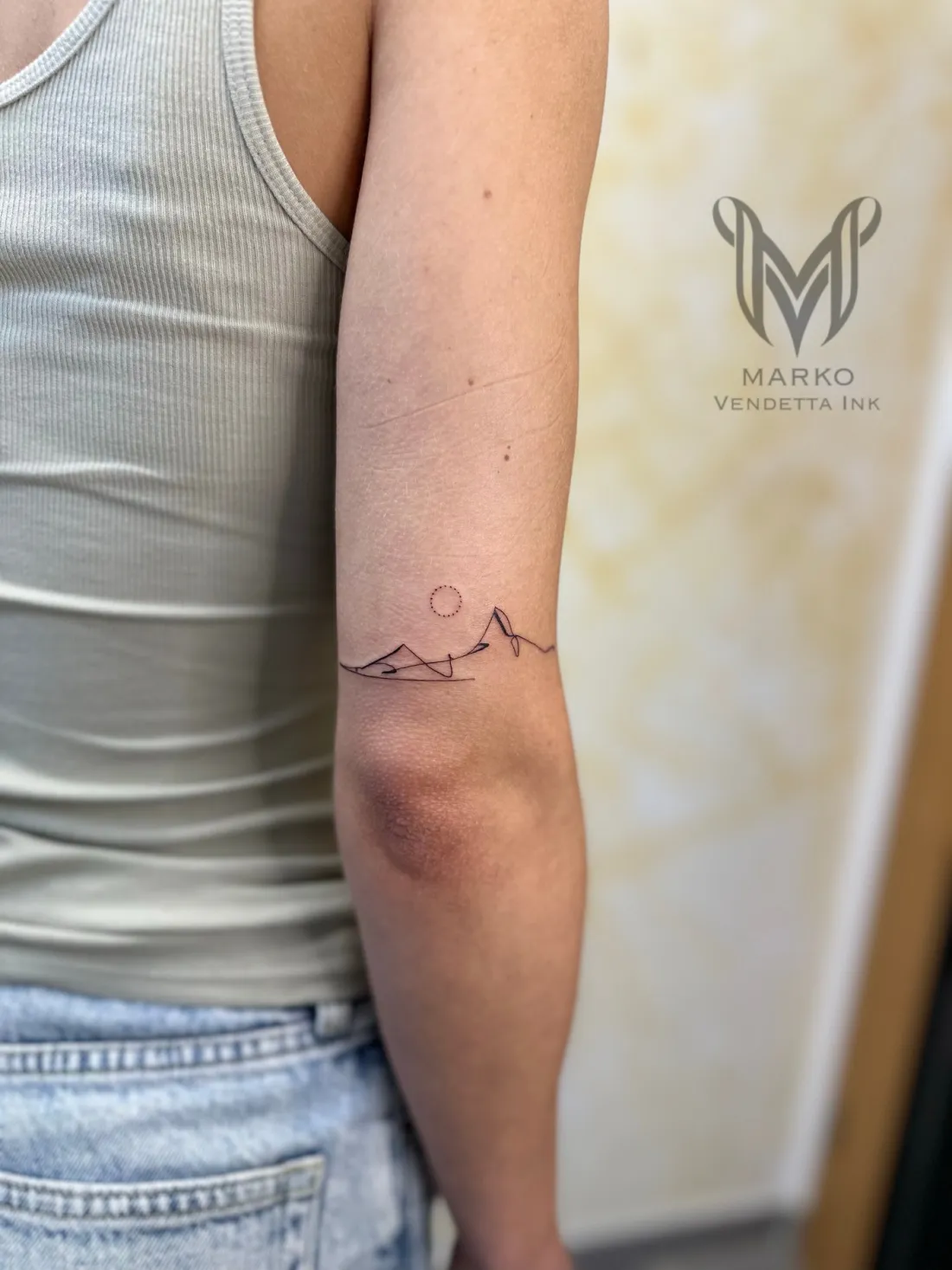 Minimalistische Bergkette mit Sonne am Oberarm — Fine Line Tattoo von Marko