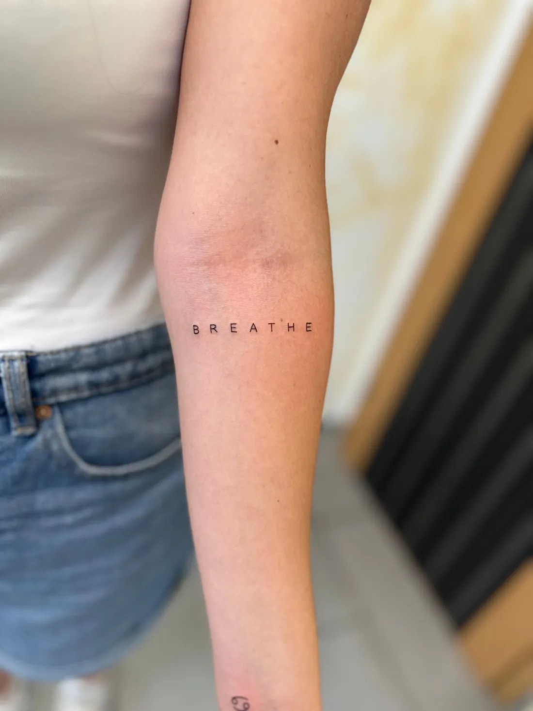 Schriftzug BREATHE auf Oberarm — Lettering Tattoo von Marko