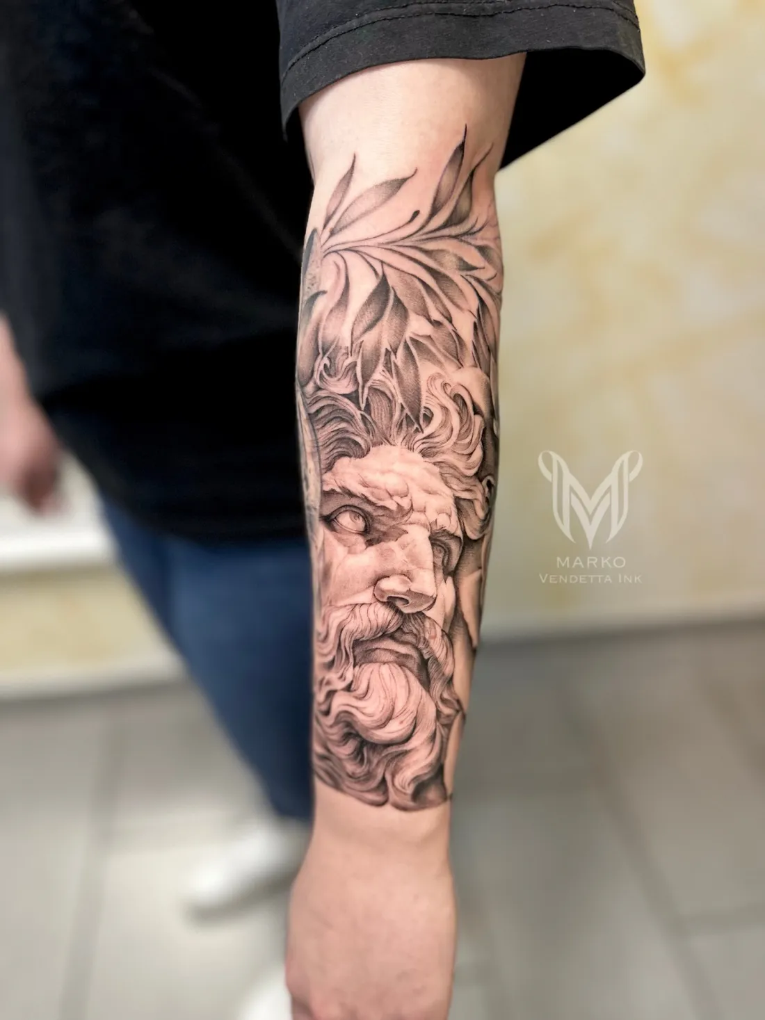 Zeus-Statue mit Lorbeerblaettern auf Unterarm — Realismus Tattoo von Marko